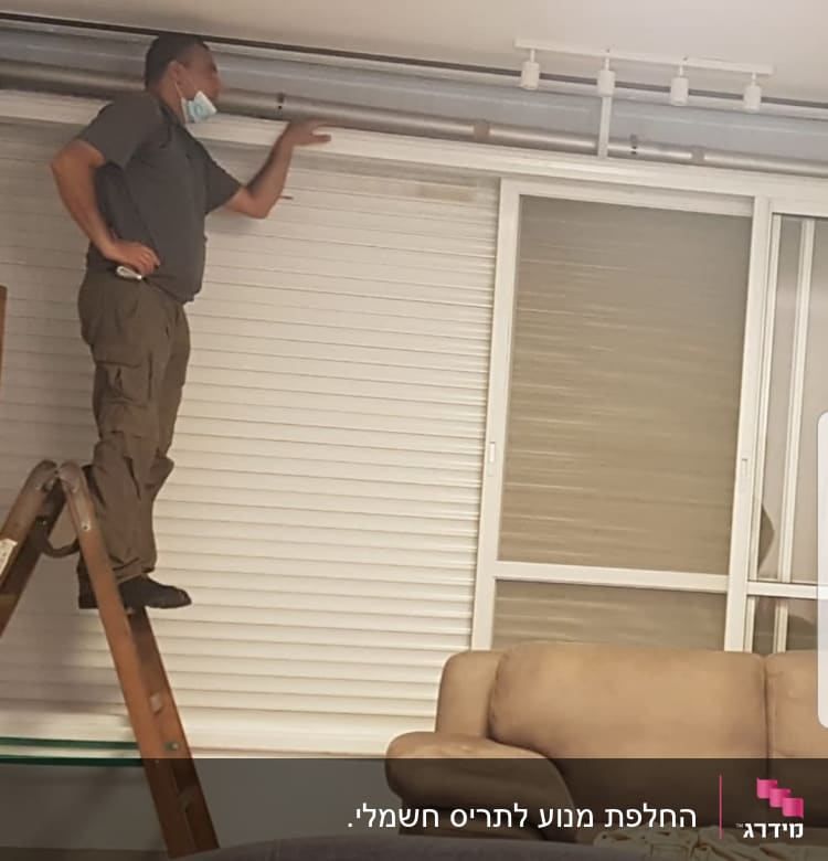 אדם על סולם מתקין תריסים בחלון